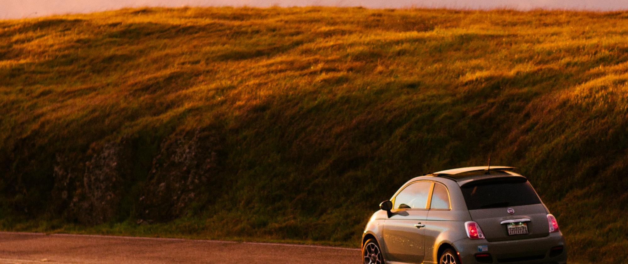 Dodrives compact vehicle on road trip in sunset